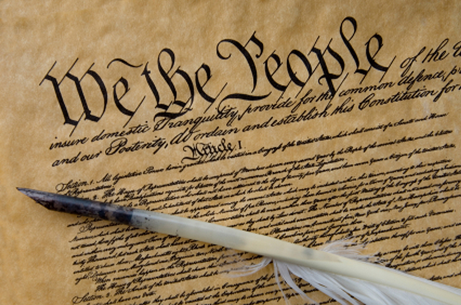 The USA Constitution with a quill pen laid on top of it
